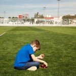 Niño sentado sobre campo de fútbol