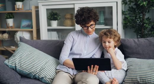 Niño utilizando una tablet mientras un adulto supervisa el uso de pantallas en la infancia