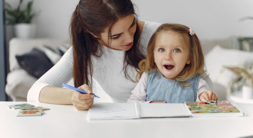 Madre estimula el lenguaje de su hija pequeña con imágenes y un cuaderno