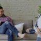 Pareja sentada en un sofá, mirando en direcciones opuestas y mostrando distanciamiento emocional.